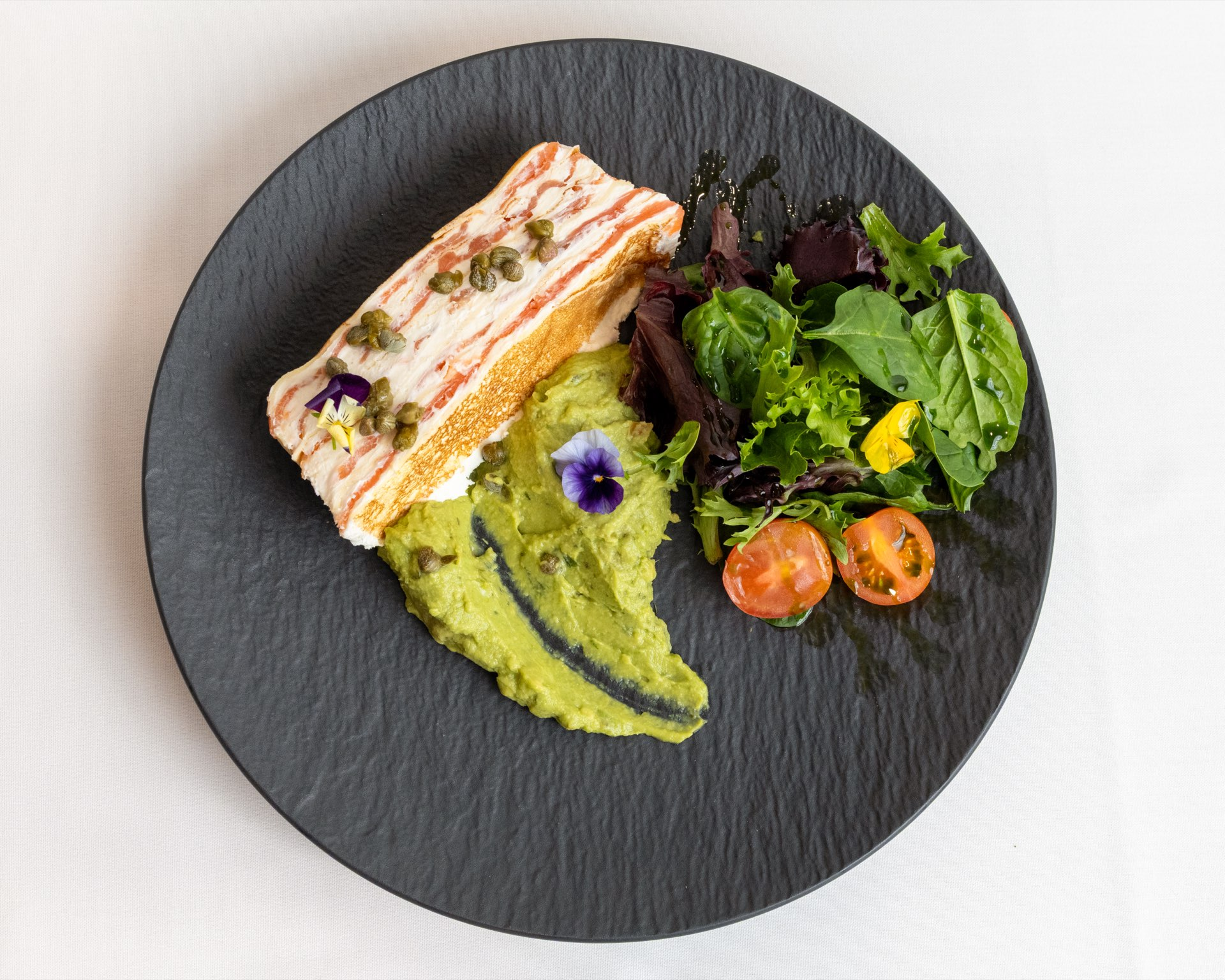 Smoked salmon with avocado and capers on dark slate