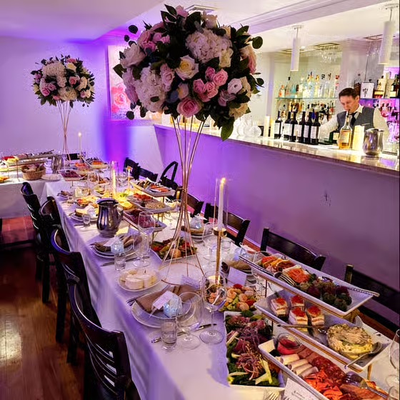 Catered buffet spread with purple ambient lighting, floral arrangement, and food display